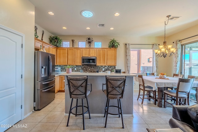 kitchen with plenty of natural light, hanging light fixtures, light tile patterned floors, and stainless steel appliances