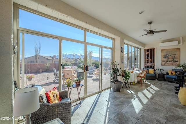 sunroom with ceiling fan, a mountain view, and a wall mounted air conditioner