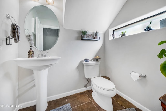 bathroom with toilet, lofted ceiling, and tile patterned flooring