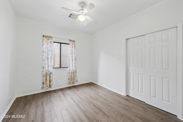 unfurnished bedroom with hardwood / wood-style floors, a closet, and ceiling fan