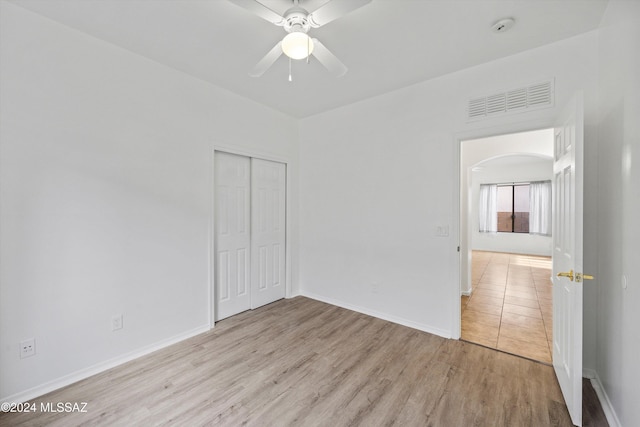 unfurnished bedroom with light hardwood / wood-style flooring, ceiling fan, and a closet