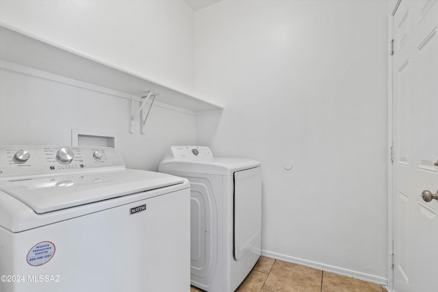 clothes washing area featuring washer and dryer and light tile patterned flooring