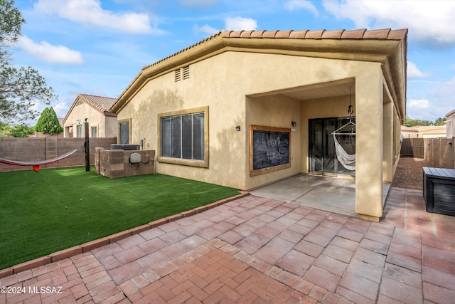 back of property with a yard and a patio