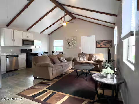 living room featuring beam ceiling, light hardwood / wood-style flooring, high vaulted ceiling, and ceiling fan