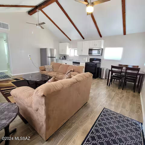 living room with beam ceiling, high vaulted ceiling, light hardwood / wood-style flooring, and ceiling fan