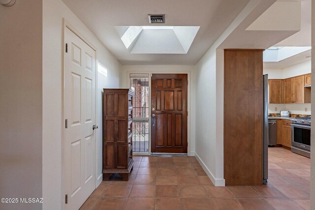 kitchen featuring a skylight, visible vents, a sink, a peninsula, and baseboards