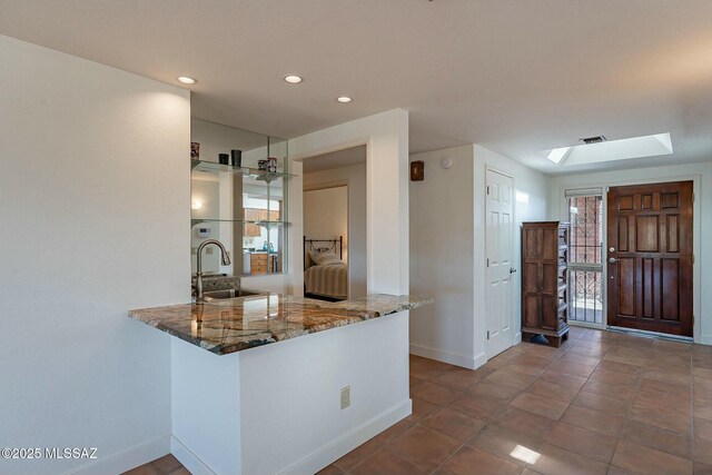 kitchen featuring brown cabinets, stainless steel appliances, visible vents, a ceiling fan, and light stone countertops