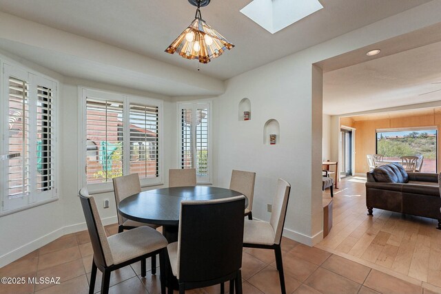 kitchen with a skylight, brown cabinets, stainless steel appliances, a sink, and light stone countertops