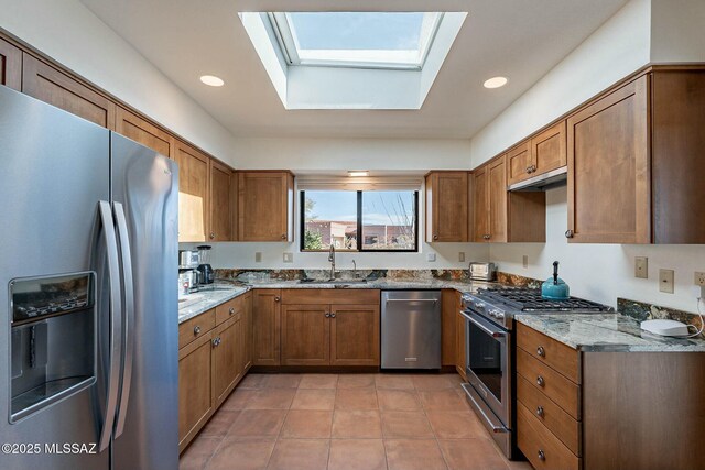 kitchen with stainless steel appliances, light stone counters, a sink, and visible vents