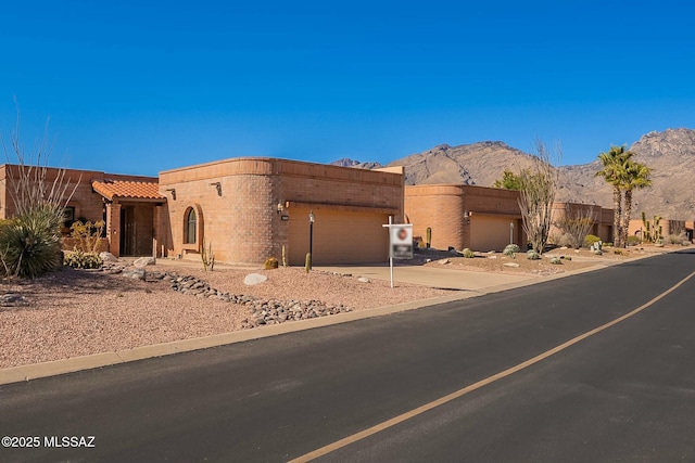 view of front of house with a garage, a tile roof, a mountain view, and driveway