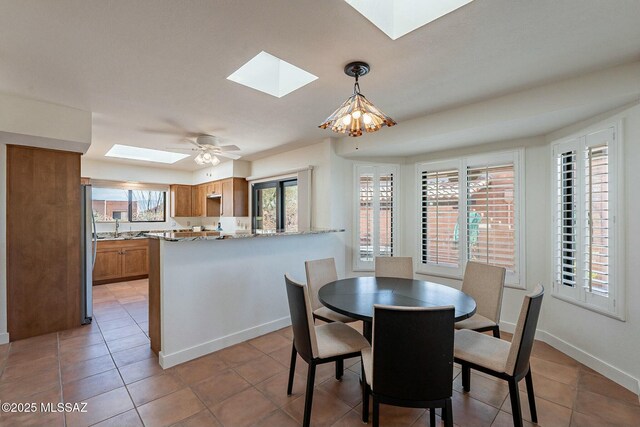 kitchen featuring appliances with stainless steel finishes, a skylight, brown cabinetry, and light stone countertops