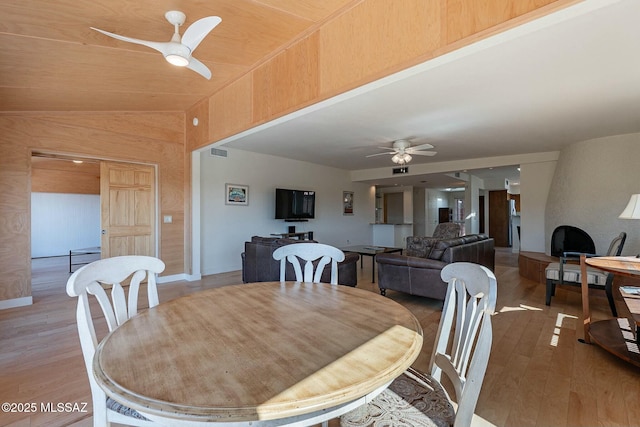 dining room with ceiling fan, wood finished floors, visible vents, and lofted ceiling