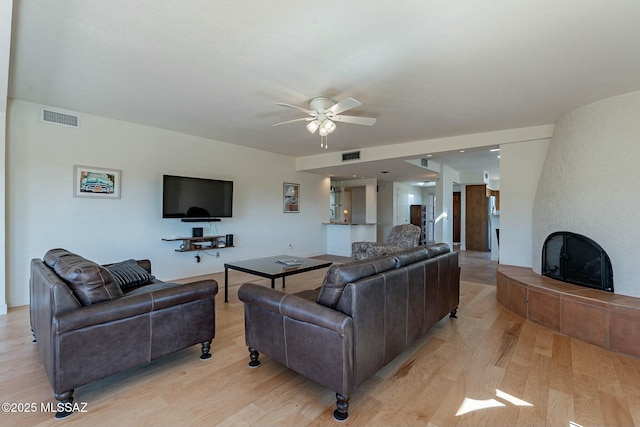 living area with visible vents, a fireplace, and light wood-style flooring