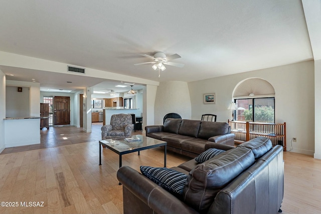 living room featuring baseboards, visible vents, ceiling fan, and light wood finished floors