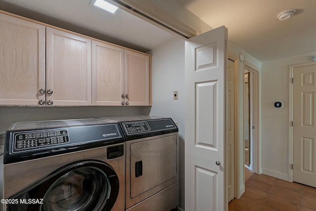 washroom featuring cabinet space, light tile patterned floors, baseboards, and separate washer and dryer