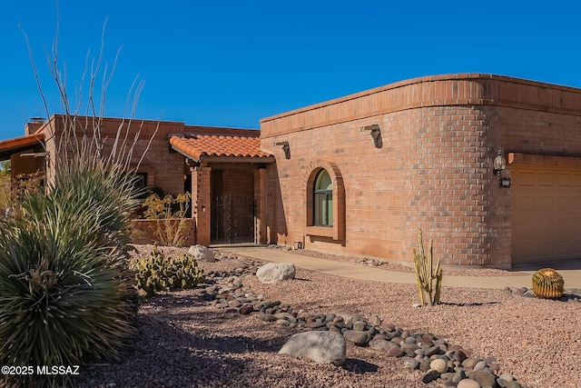 view of front of property featuring an attached garage, a tile roof, and brick siding