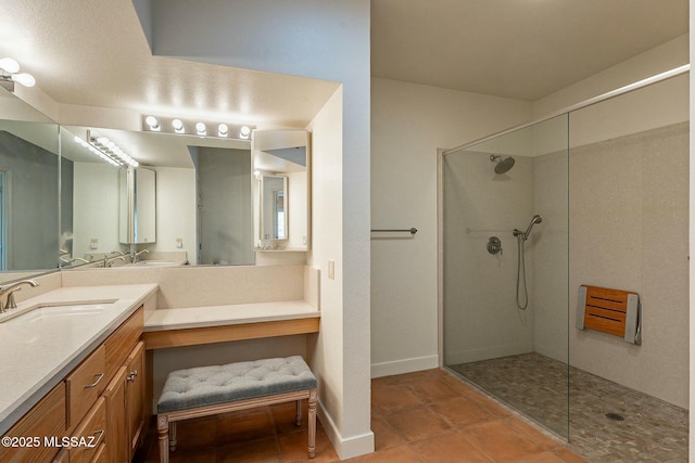 bathroom with tile patterned floors, vanity, baseboards, and a walk in shower