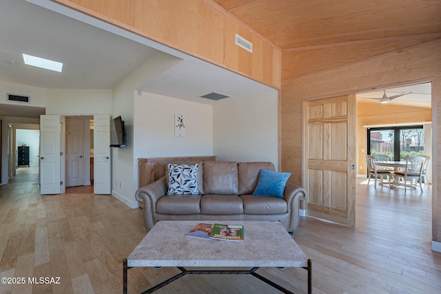 living area with light wood-type flooring, visible vents, and a skylight