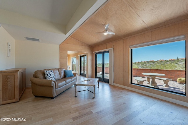 living area featuring baseboards, visible vents, a ceiling fan, vaulted ceiling, and light wood-type flooring