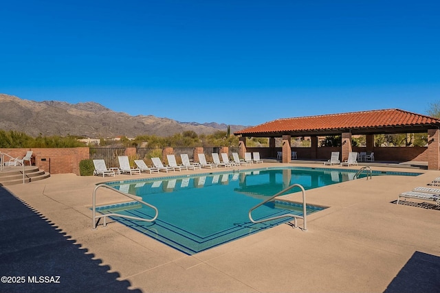 community pool with a patio, fence, and a mountain view