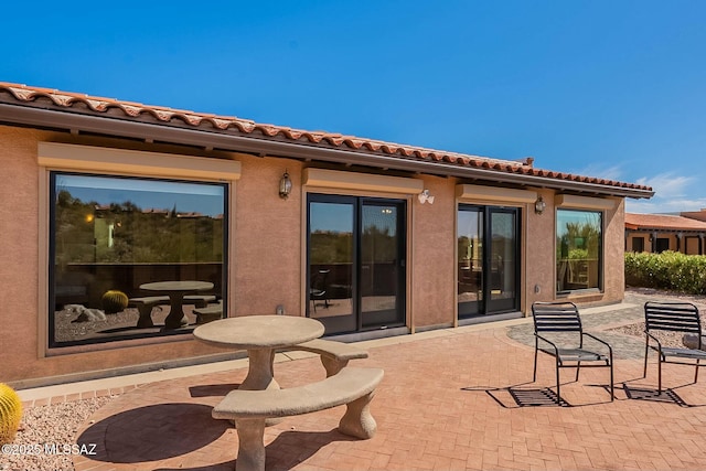 back of house with a patio area, a tiled roof, and stucco siding