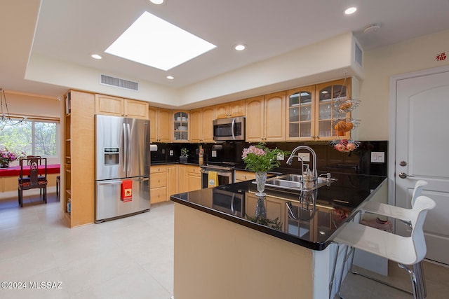 kitchen with stainless steel appliances, kitchen peninsula, decorative backsplash, sink, and a skylight