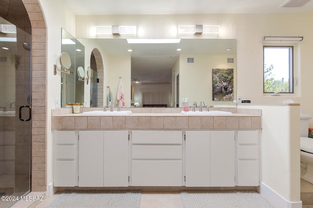 bathroom featuring tile patterned flooring, vanity, toilet, and a shower with door