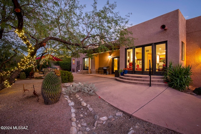 back house at dusk featuring a patio