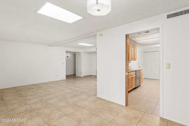 tiled empty room with a textured ceiling