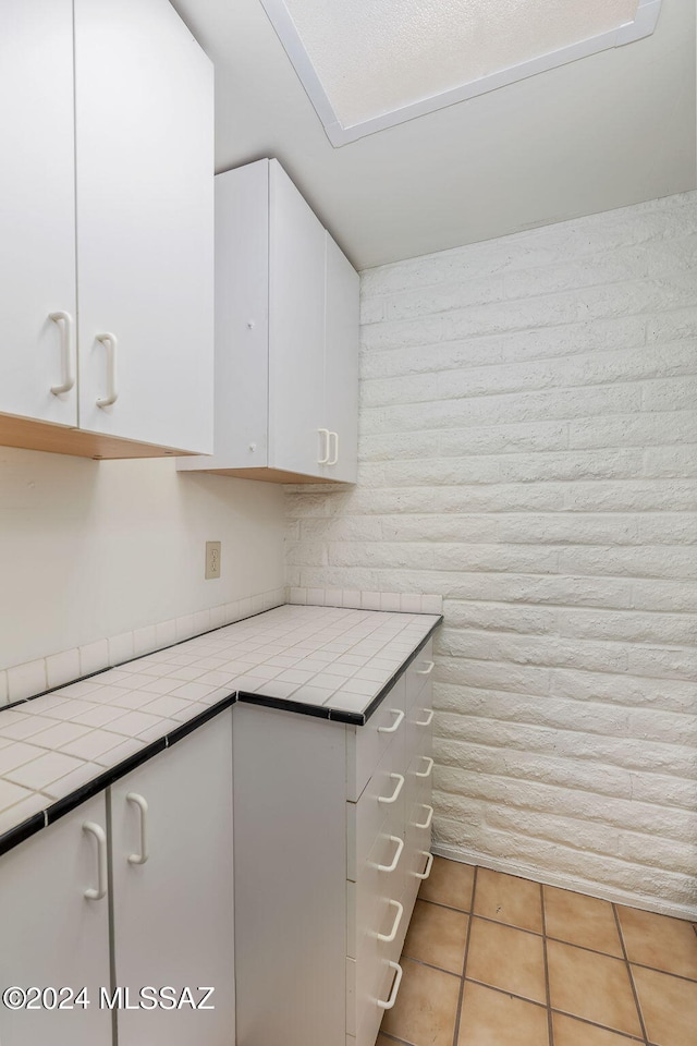 kitchen with tile countertops, light tile patterned flooring, and white cabinets