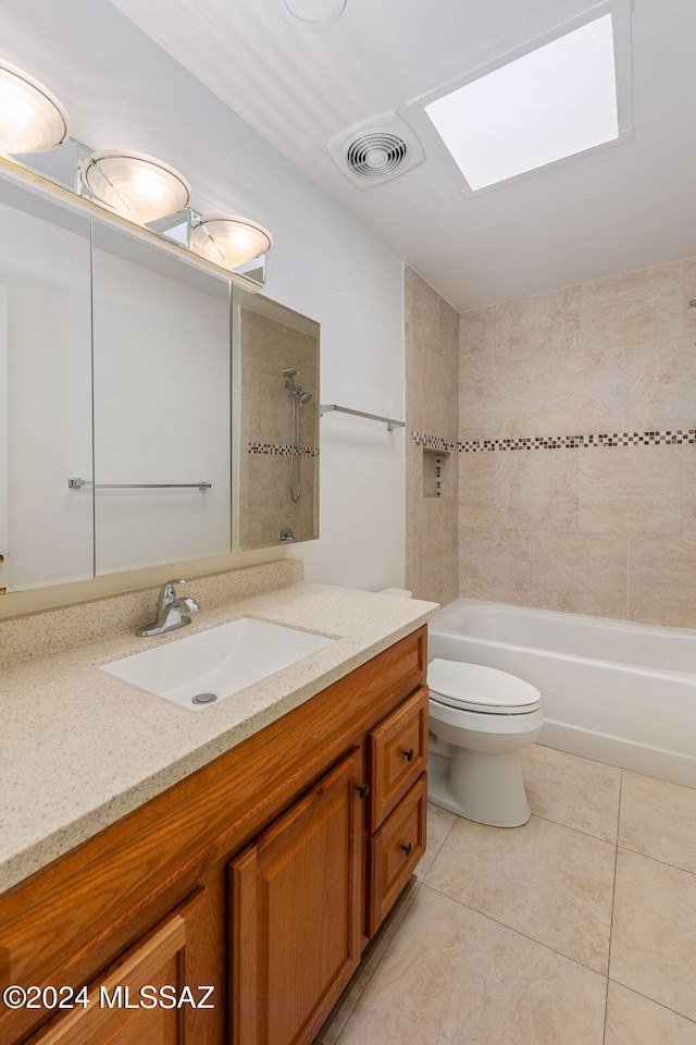 full bathroom with toilet, tile patterned floors, tiled shower / bath combo, vanity, and a skylight