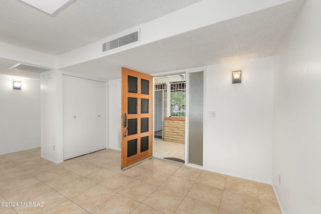 spare room featuring a textured ceiling and light tile patterned floors