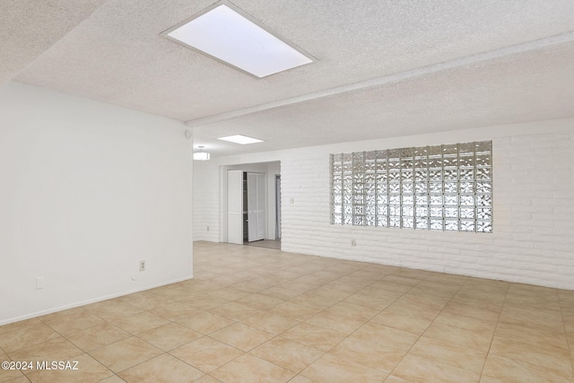 spare room featuring a textured ceiling and brick wall