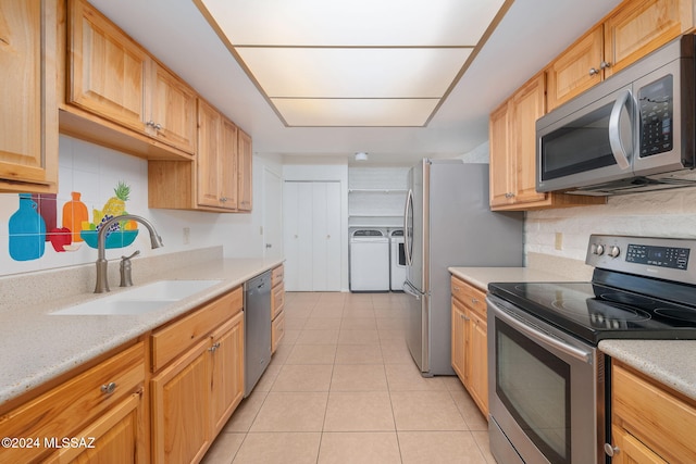 kitchen with stainless steel appliances, light tile patterned flooring, sink, light brown cabinetry, and washing machine and clothes dryer