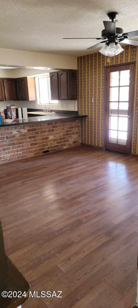 interior space featuring ceiling fan, a healthy amount of sunlight, dark hardwood / wood-style flooring, and a textured ceiling