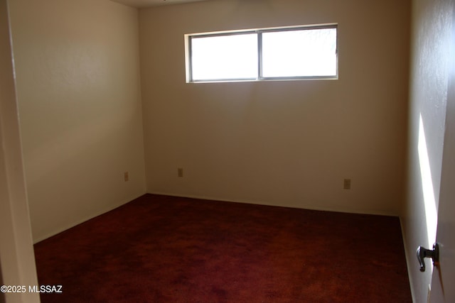 unfurnished room featuring dark carpet