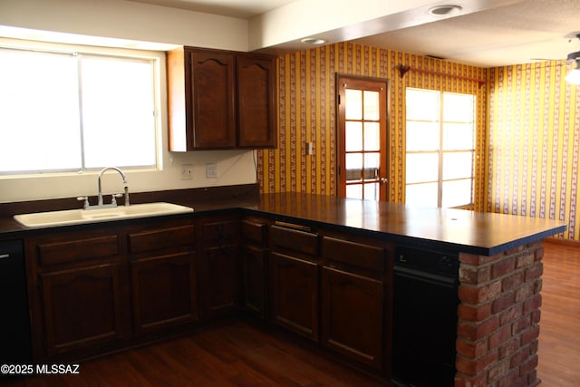 kitchen featuring kitchen peninsula, black dishwasher, dark hardwood / wood-style floors, dark brown cabinetry, and sink