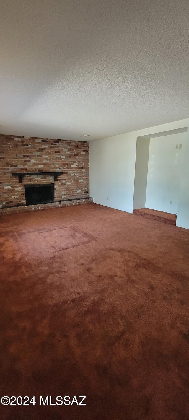 unfurnished living room with carpet floors, a fireplace, and a textured ceiling