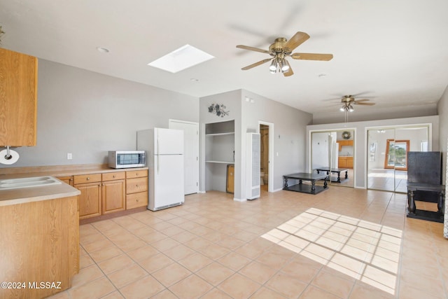 kitchen featuring white refrigerator, light brown cabinetry, sink, a skylight, and ceiling fan