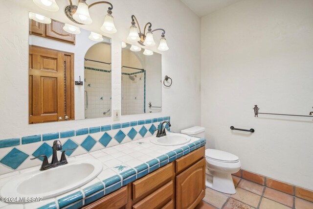 bathroom with vanity, toilet, decorative backsplash, and tiled shower