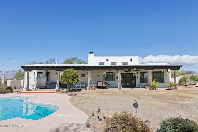 rear view of property with ceiling fan, a fenced in pool, and a patio