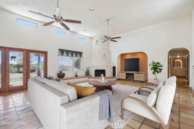 tiled living room featuring french doors, ceiling fan, and a high ceiling