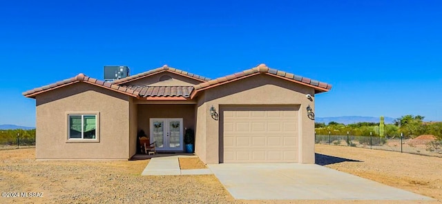 view of front of home featuring a mountain view, french doors, a garage, and central air condition unit