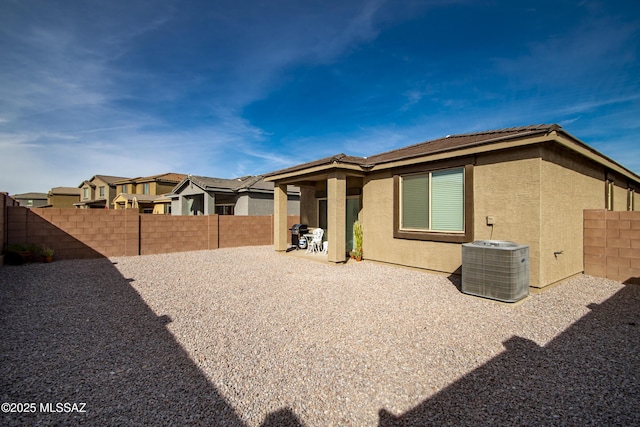 back of house with central air condition unit, a fenced backyard, a patio, and stucco siding