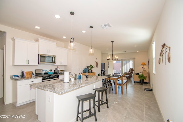 kitchen with appliances with stainless steel finishes, a breakfast bar, white cabinets, and an island with sink