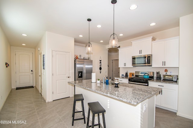 kitchen featuring white cabinets, an island with sink, a breakfast bar, stainless steel appliances, and recessed lighting