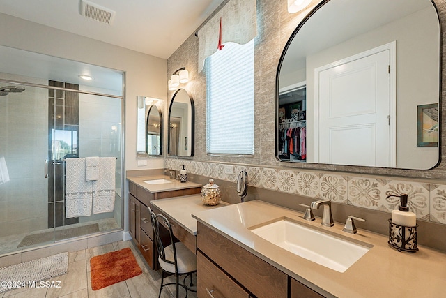 bathroom with an enclosed shower, vanity, tile patterned floors, and backsplash