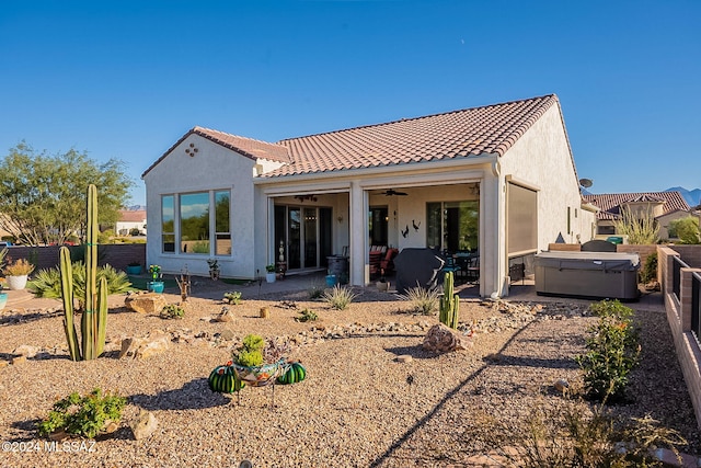 back of property with ceiling fan, a hot tub, and a patio area