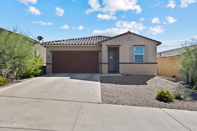 view of front of home with an attached garage, driveway, a tiled roof, and stucco siding