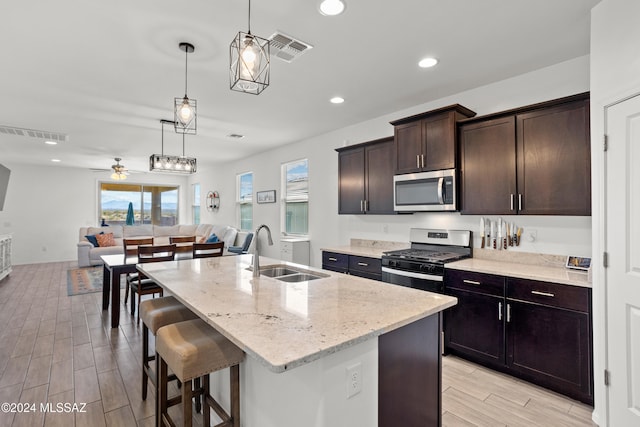 kitchen with a kitchen island with sink, light hardwood / wood-style floors, appliances with stainless steel finishes, and sink